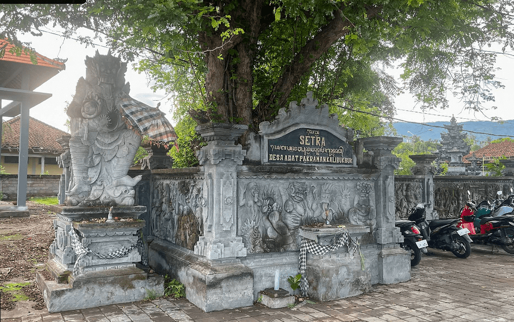 Fotografie balijského hřbitova umístěného hned u parkoviště na pláži Lovina na severu Bali. Tradiční kamenné stavby, které si turisté často pletou s chrámem.