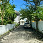 Série fotografií exteriéru a interiéru čistého dvoupodlažního domu v bezpečné rezidenční čtvrti v Sanuru na Bali. Ukázka světlé ložnice, moderní koupelny a upravené ulice.