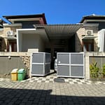 Série fotografií exteriéru a interiéru čistého dvoupodlažního domu v bezpečné rezidenční čtvrti v Sanuru na Bali. Ukázka světlé ložnice, moderní koupelny a upravené ulice.