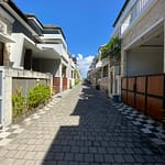 Série fotografií exteriéru a interiéru čistého dvoupodlažního domu v bezpečné rezidenční čtvrti v Sanuru na Bali. Ukázka světlé ložnice, moderní koupelny a upravené ulice.