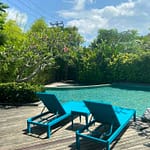 Koláž pěti fotografií z pronajatého domku v rezidenci Royal Garden na Nusa Dua, Bali. Zobrazuje sdílený bazén s lehátky, vjezd s autem a čistý interiér obývacího pokoje a dvou ložnic.