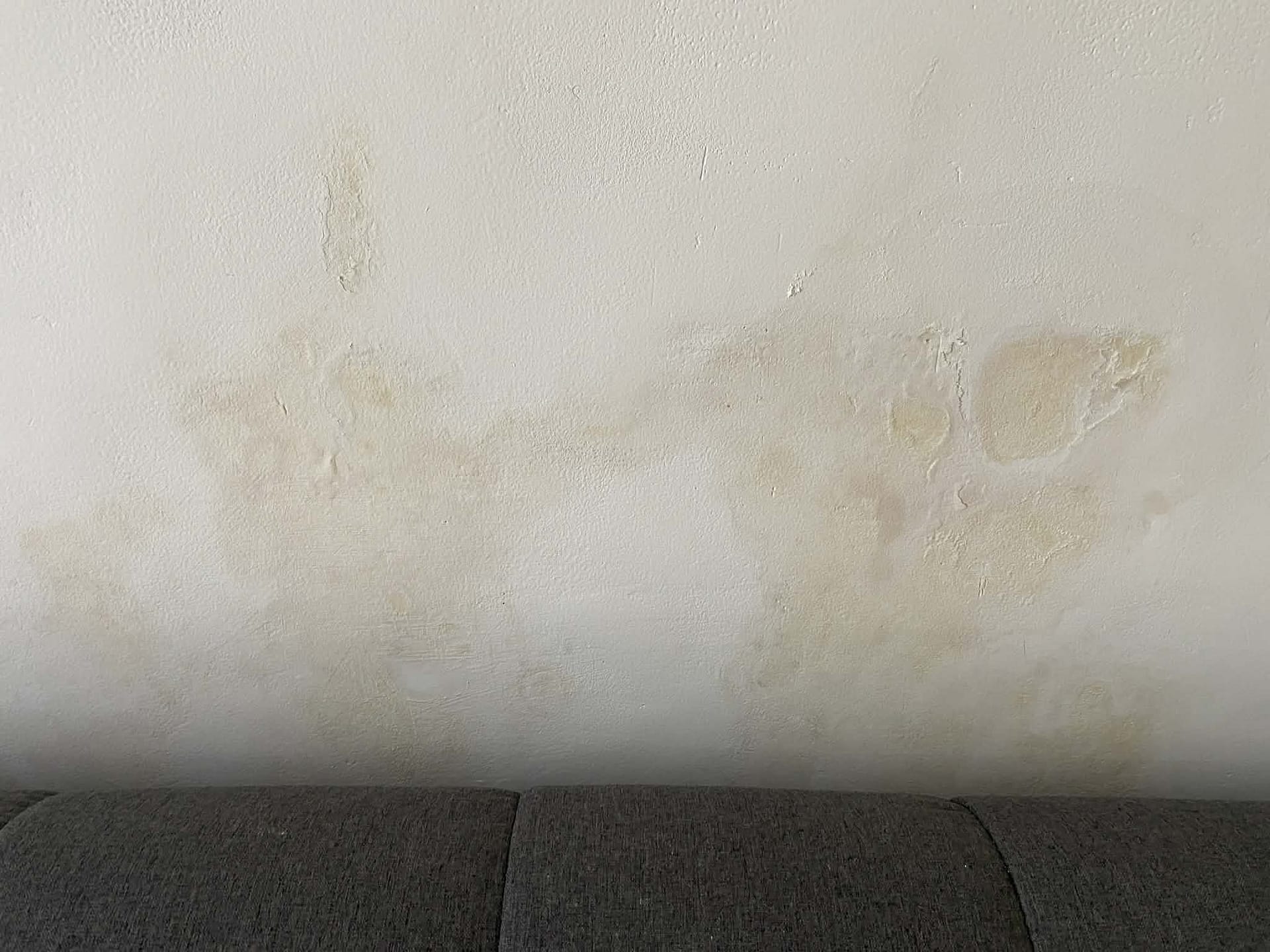 Detailní fotografie silné plísně na zdi uvnitř pronajímaného domu na Bali. Ukázka problému s vlhkostí a nekvalitní stavbou.